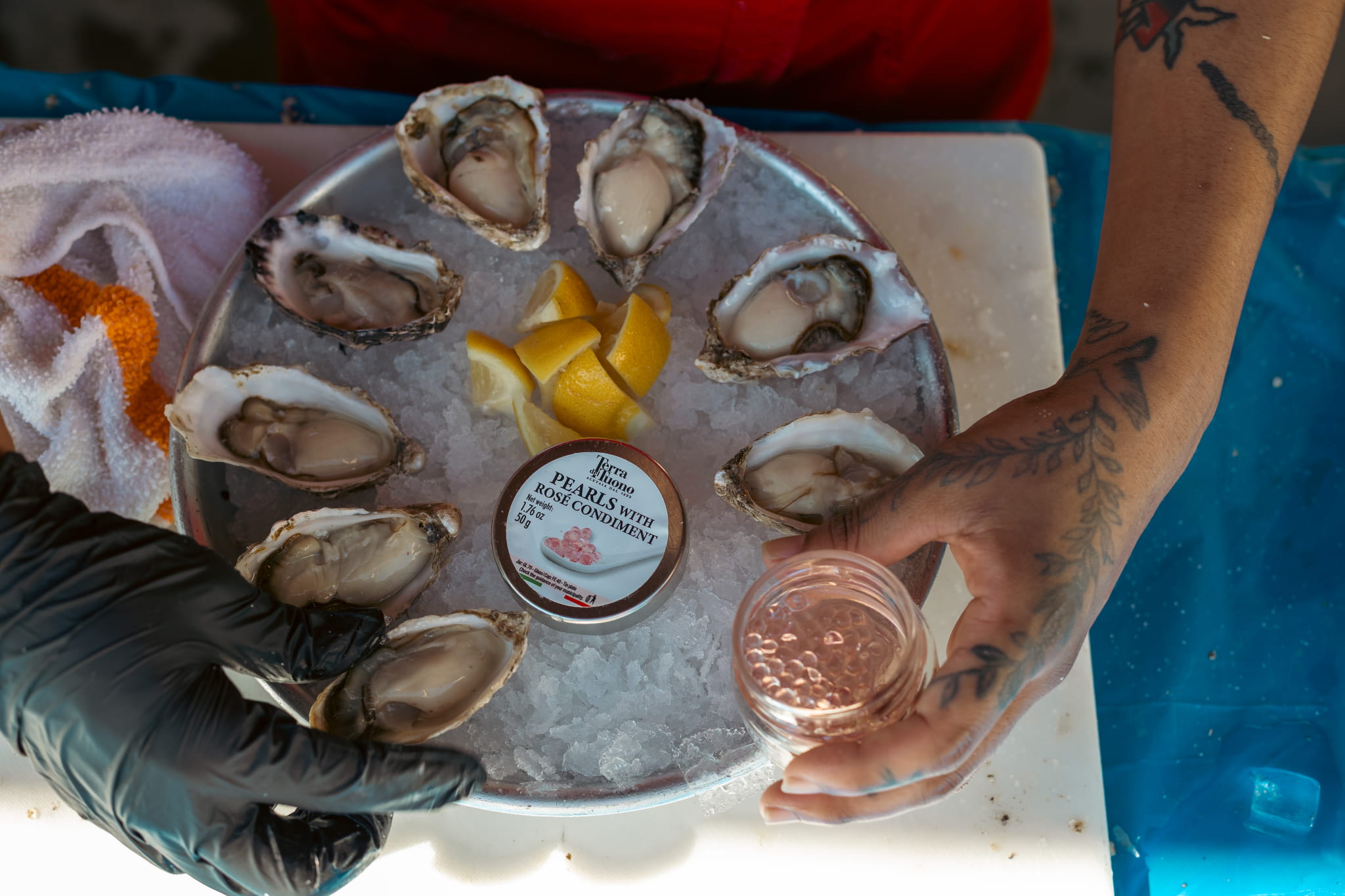 An overhead platter of freshly shucked oysters on ice with lemon and rosé pearls at a Shuck Off™ private event